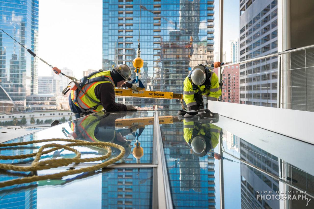 Workers prepare to install a piece of the curtain wall on Wolf Point East