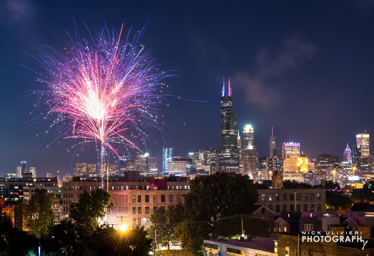 A solo firework bursts in front of the skyline 