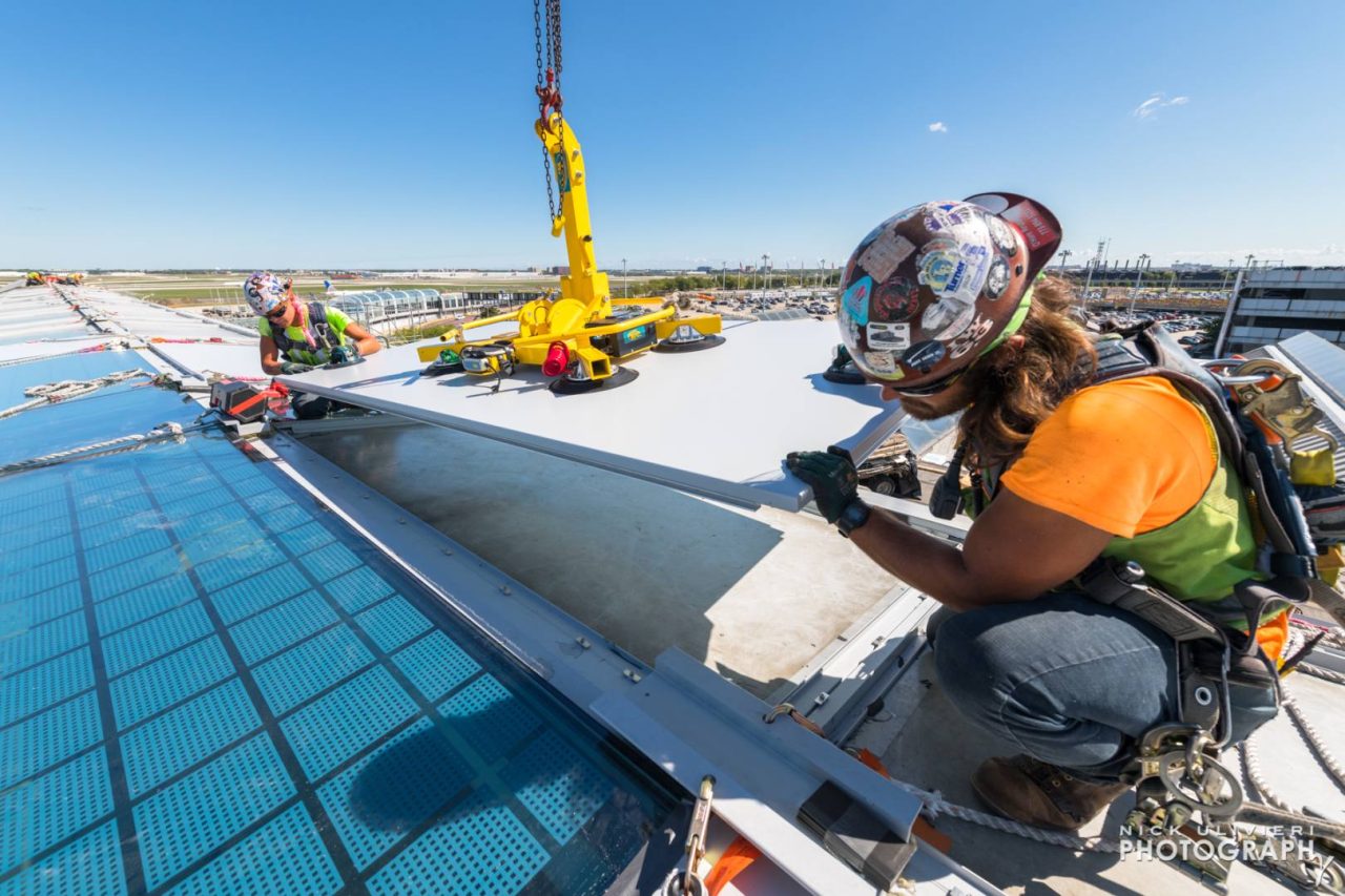 A metal spandrel panel is slowly guided into place