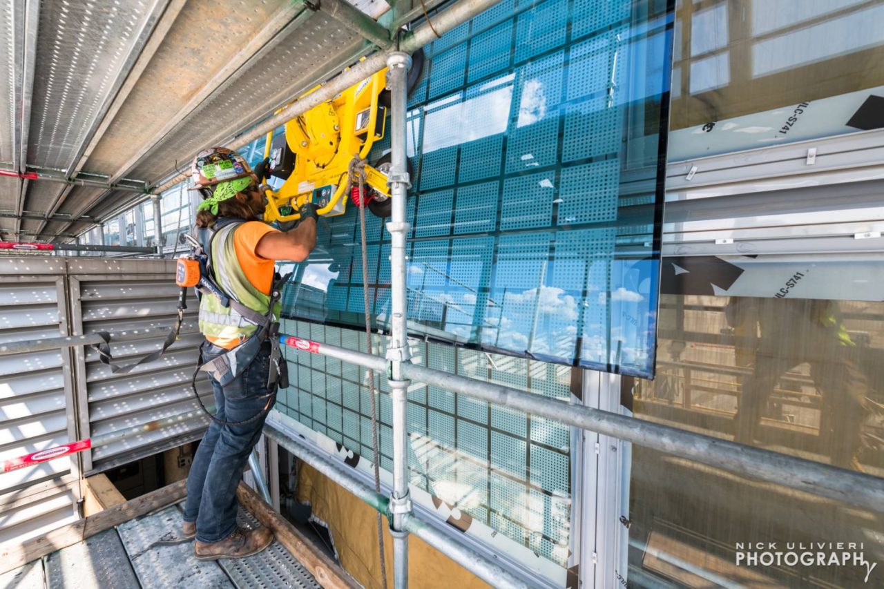 A vertical pane of glass for the base of the barrel vault is cautiously directed into place