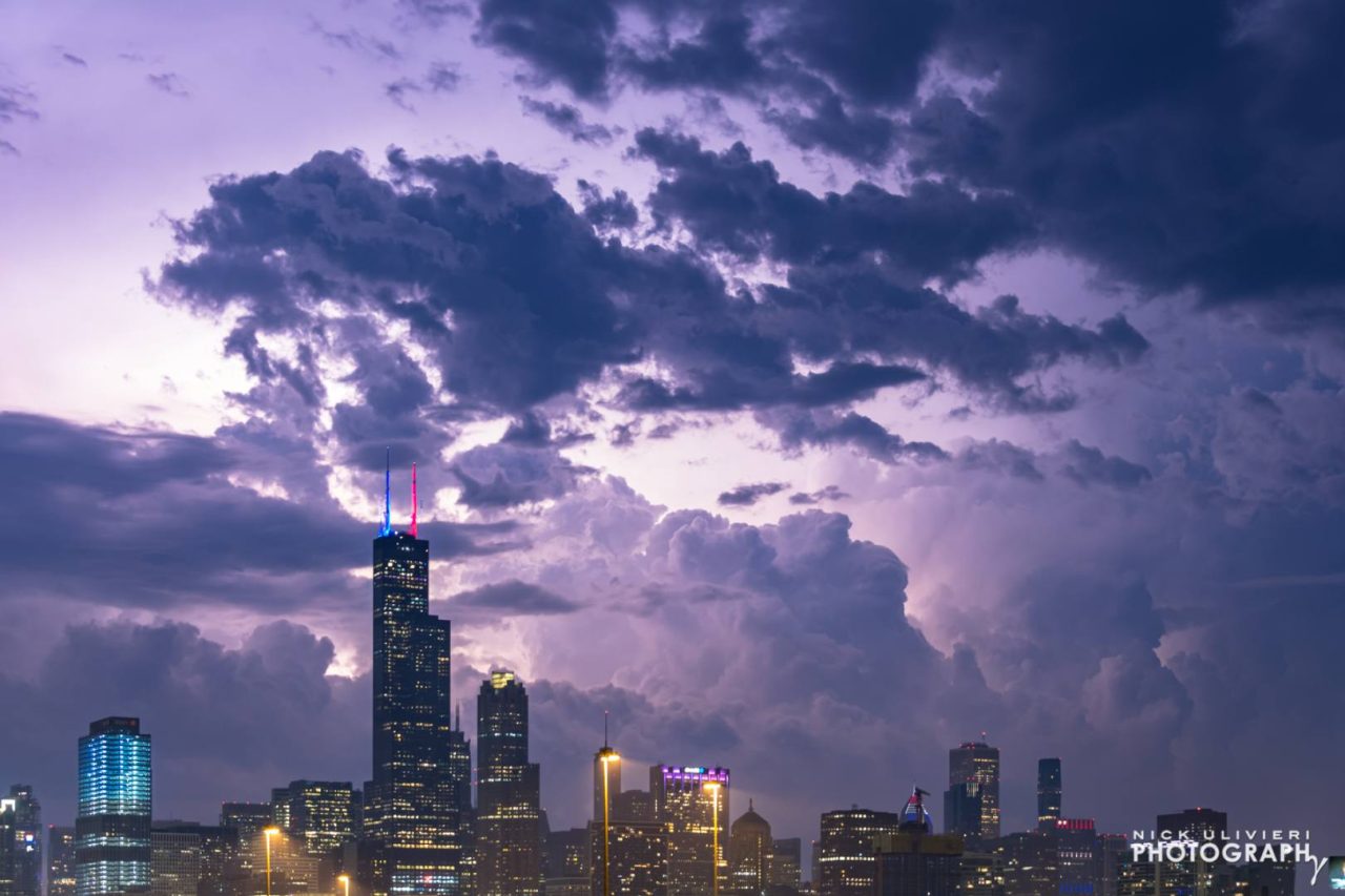 Distant, bright lightning illuminates the sky as a nighttime storm approaches